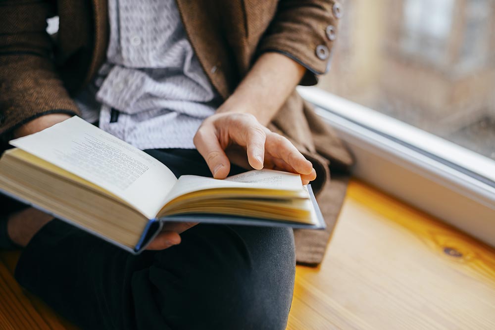 a woman reading a book by a window