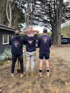 Three people facing away from the camera with the same logo on their shirts