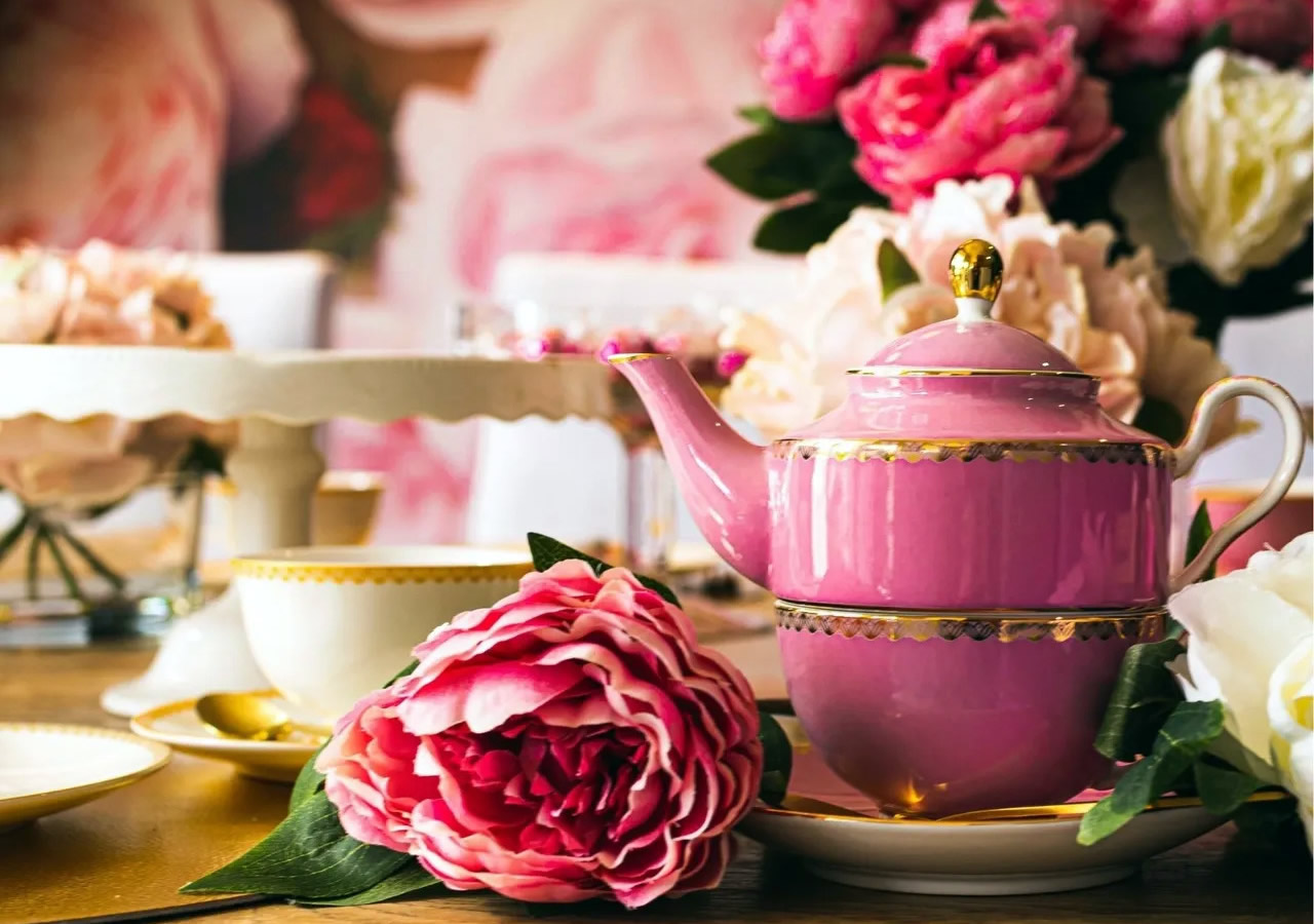 Photo of a teapot with pink flowers all around it.