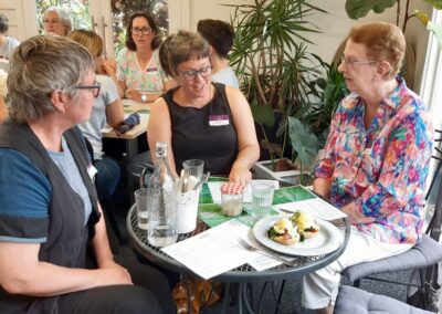 Group of women sitting around a lunch table in a cafe chatting