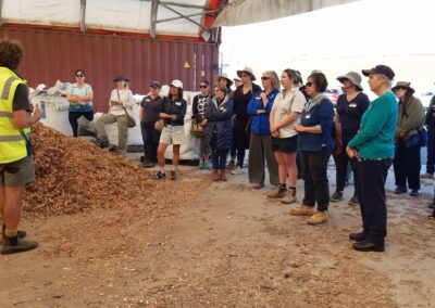 Group of people in a shed with piles of mulch.